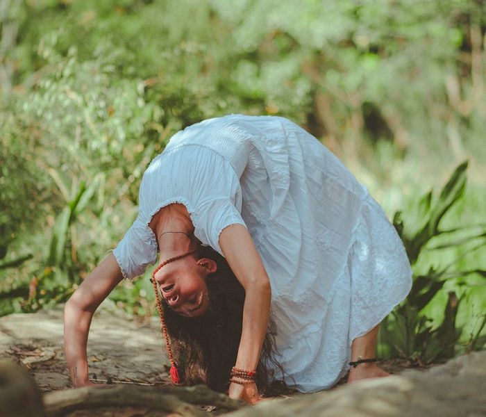 Woman stretching gracefully outdoors in a green park at sunrise.